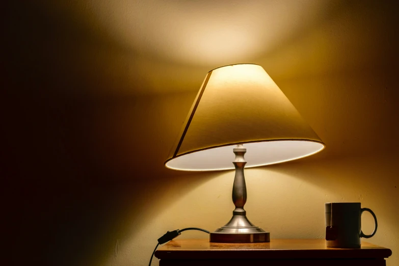 a lamp and a cup on a nightstand