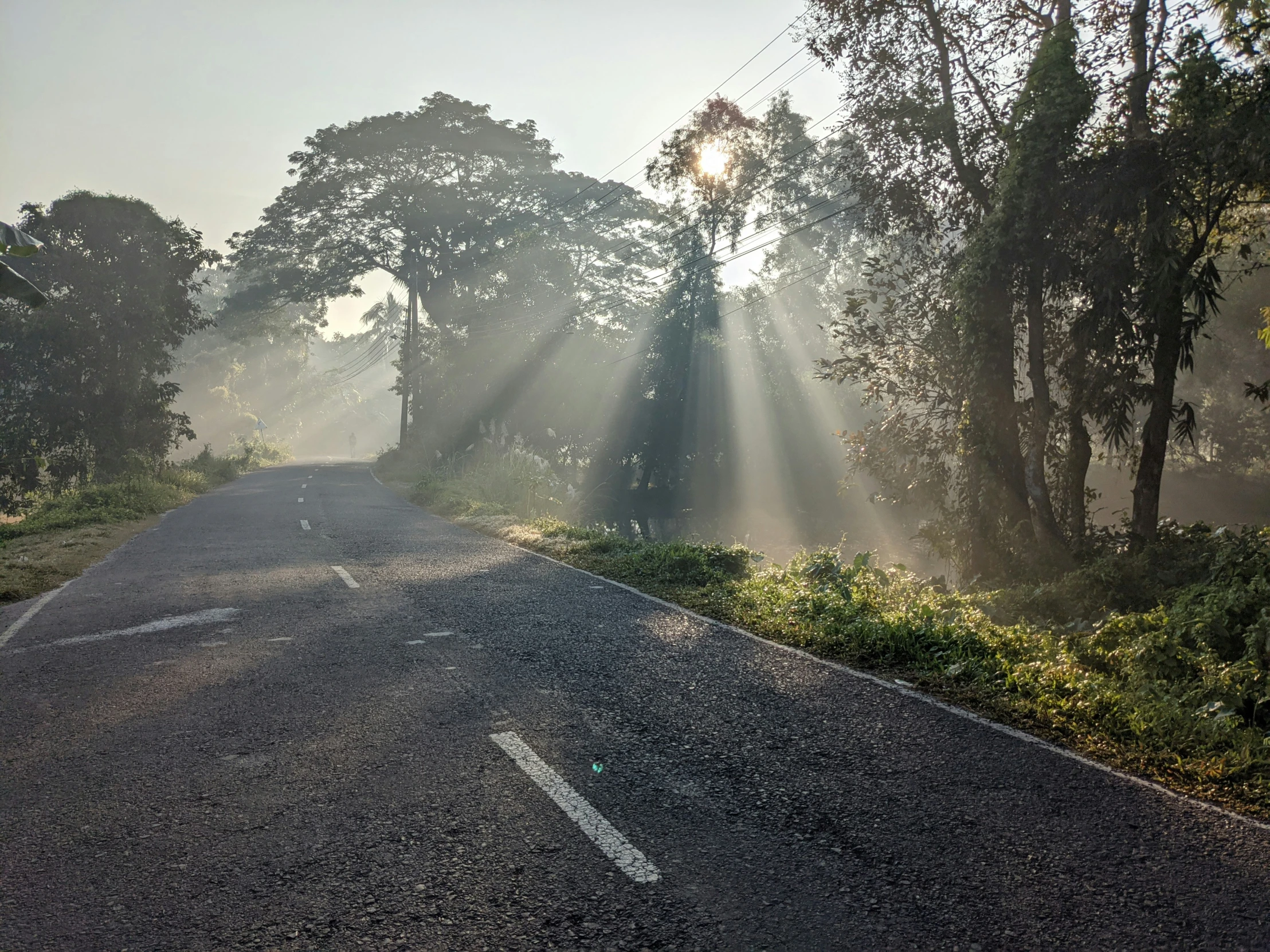 a po taken from an empty road at dusk with sun beams hitting