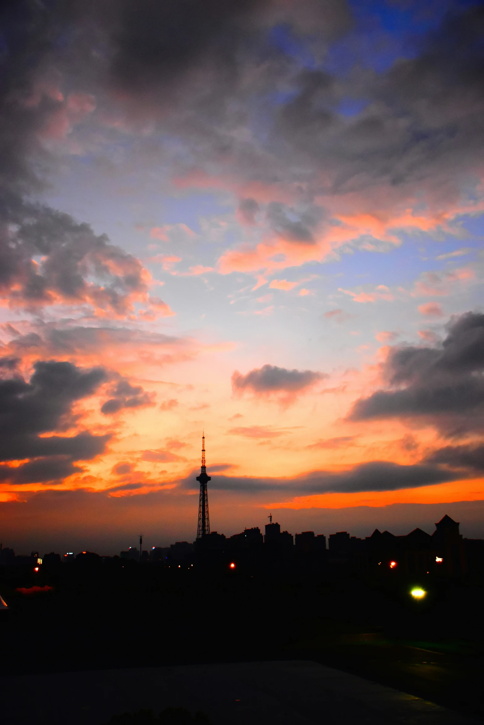 a bright orange and red cloudy sky with some buildings