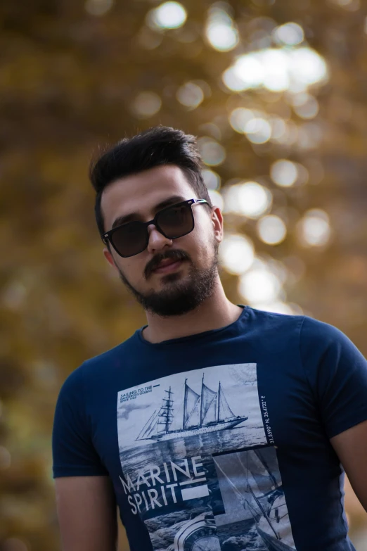 a man wearing sunglasses in front of a golden tree