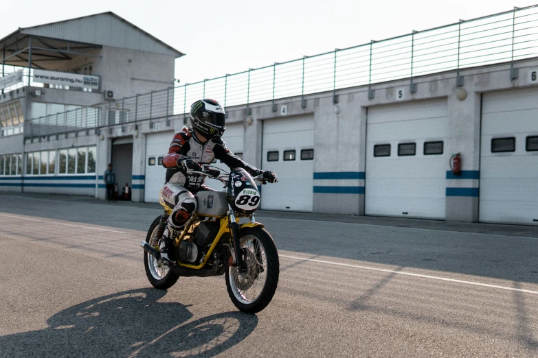 a motorcyclist riding on the road in front of garages