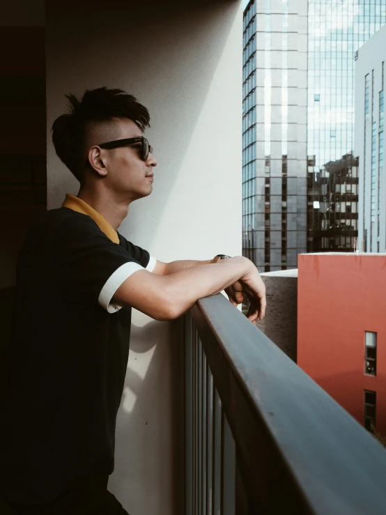 a young man leans over a balcony railing