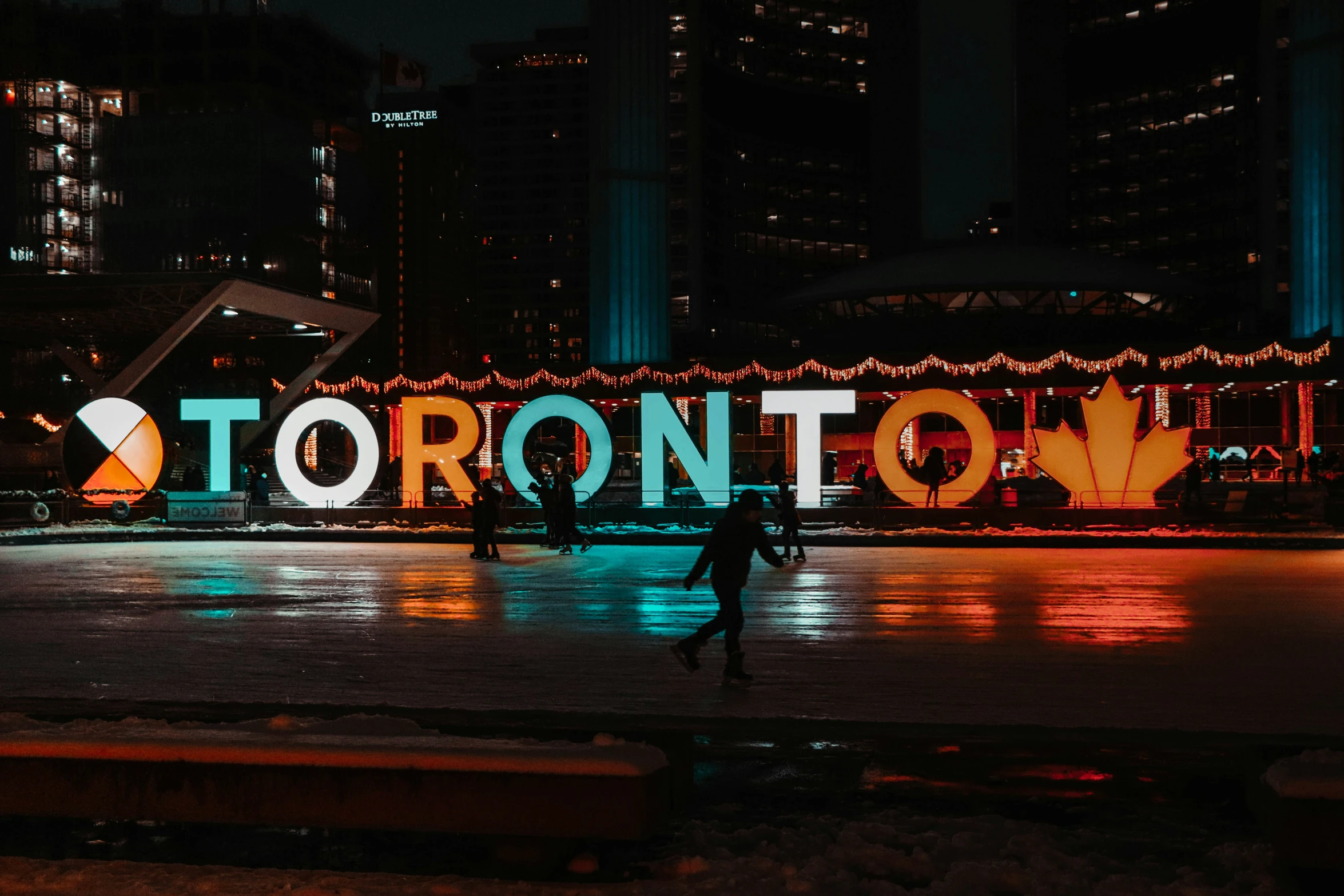 a dark cityscape with a large toronto sign at night