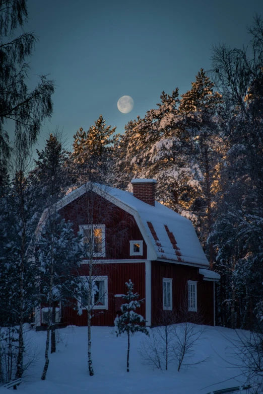 a home on a snow covered slope and a rising moon above it