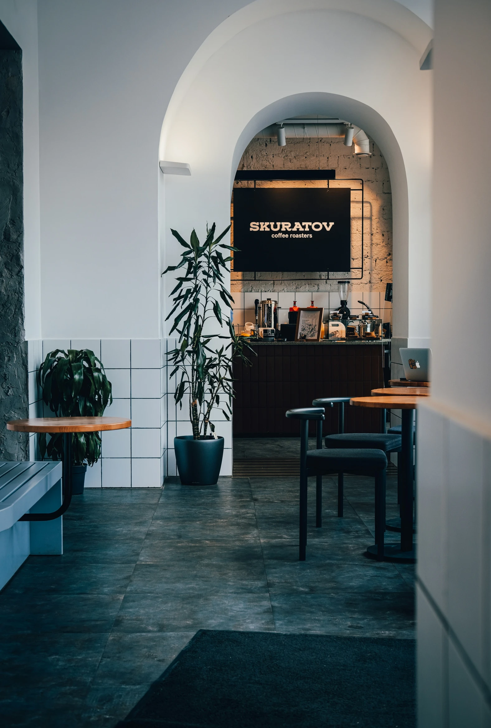 a bar with wood tables and stools next to a black wall