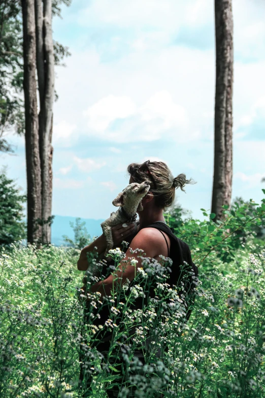 a girl in a meadow with trees and clouds behind her