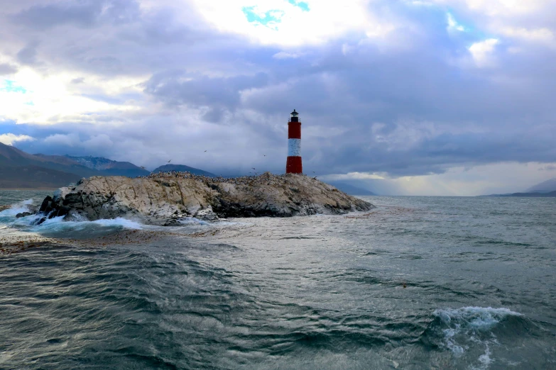 a lighthouse on a small rock with the ocean below