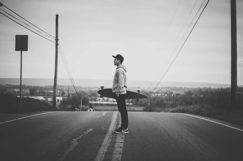 a man in a hat and sweater with skateboard looking at a camera