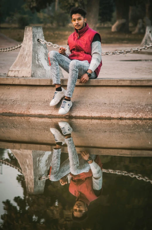 a man sitting on a wall next to a body of water