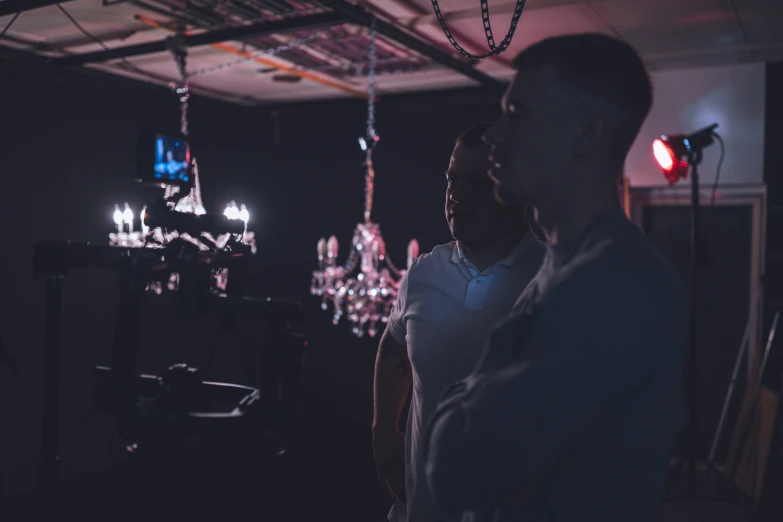 two people standing together in a room with chandeliers and lights