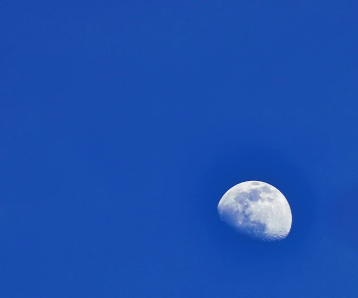 the moon is visible through a blue sky