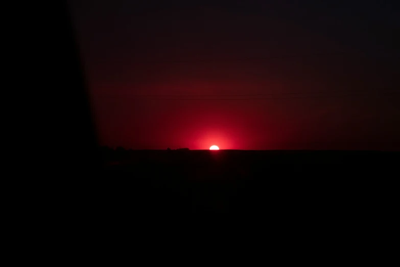 the sun is setting over a field as seen from inside an airplane