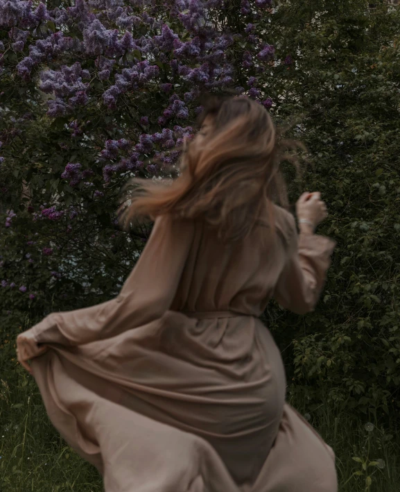 a woman standing in the grass with her hair in a wind