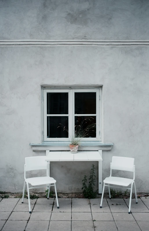 two chairs are facing a table with a plant in the window