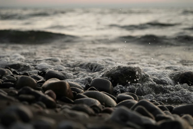 closeup of stones, rocks and water with waves coming in on them