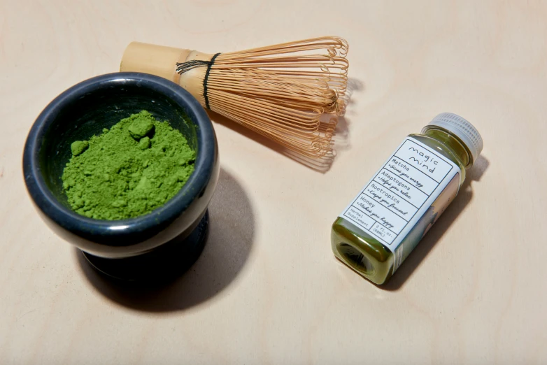 the powdered greens are in a bowl and next to a match spoon