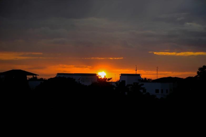 the sun rises over some buildings from a distance