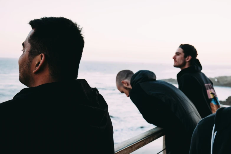 two men standing next to each other near the ocean