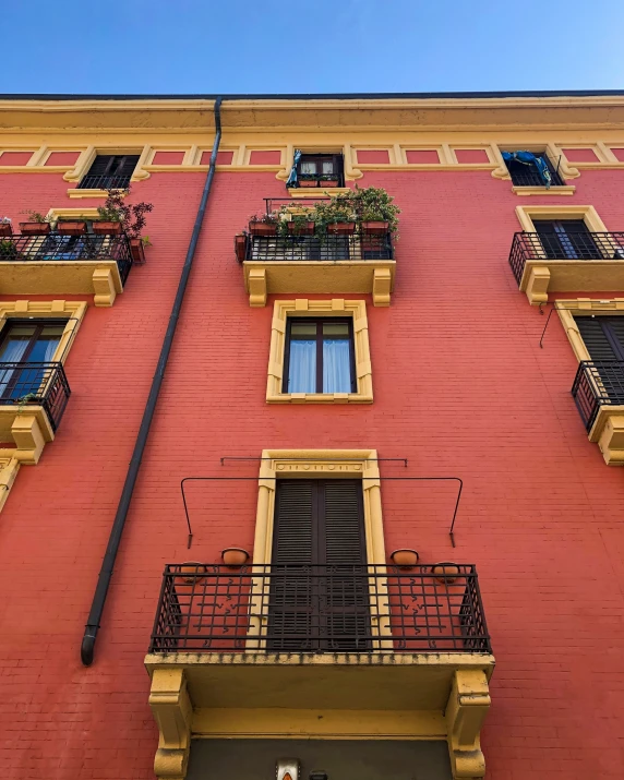 a red building with many balconies and plants