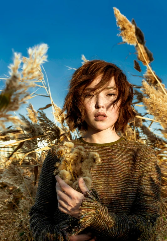 a young woman with frizzy hair standing in tall grasses