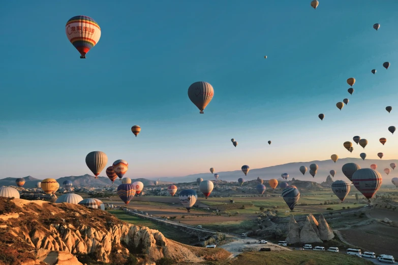  air balloons float over a hilly landscape