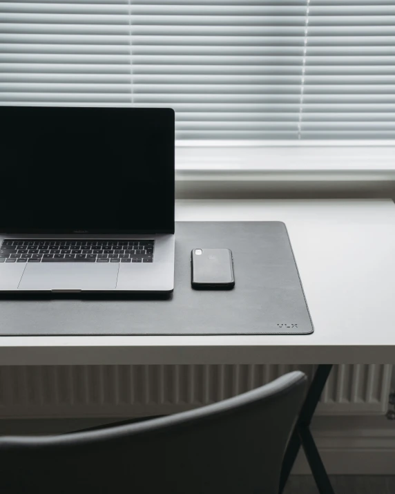 a laptop, mouse pad and a cell phone on a desk