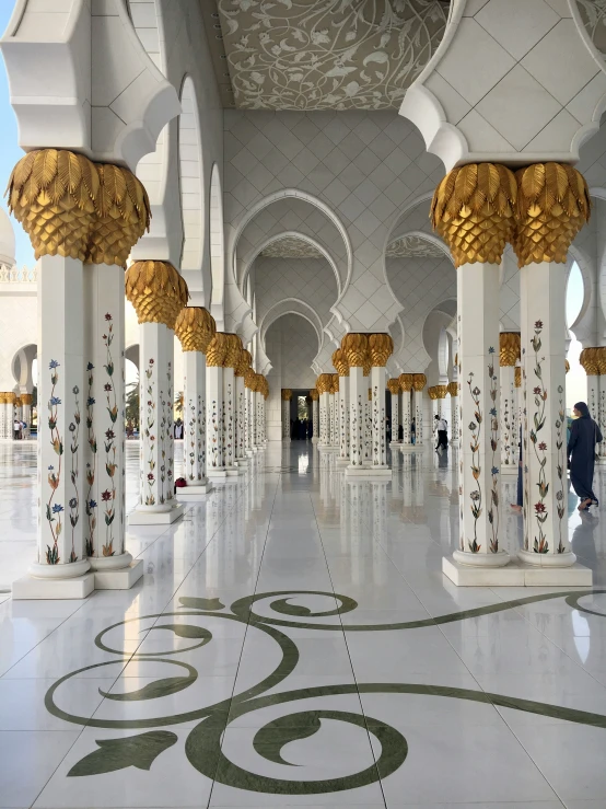 a large white corridor with elaborate white columns and gold pillars