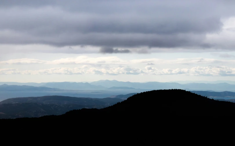 dark clouds in the sky with a mountain in the background