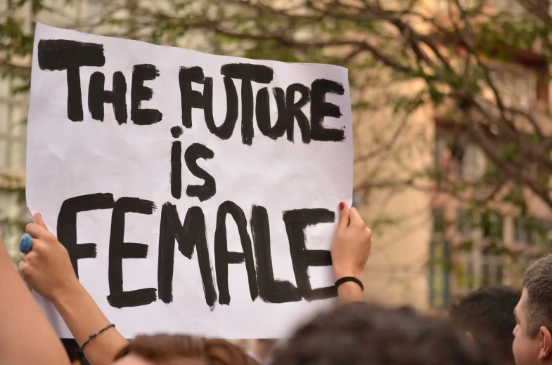 a woman holding a protest sign in the middle of the street