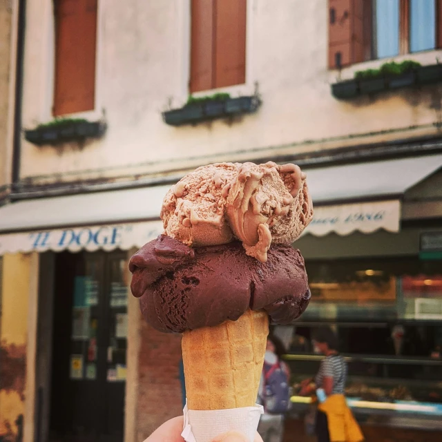 a person is holding up an ice cream cone on the street