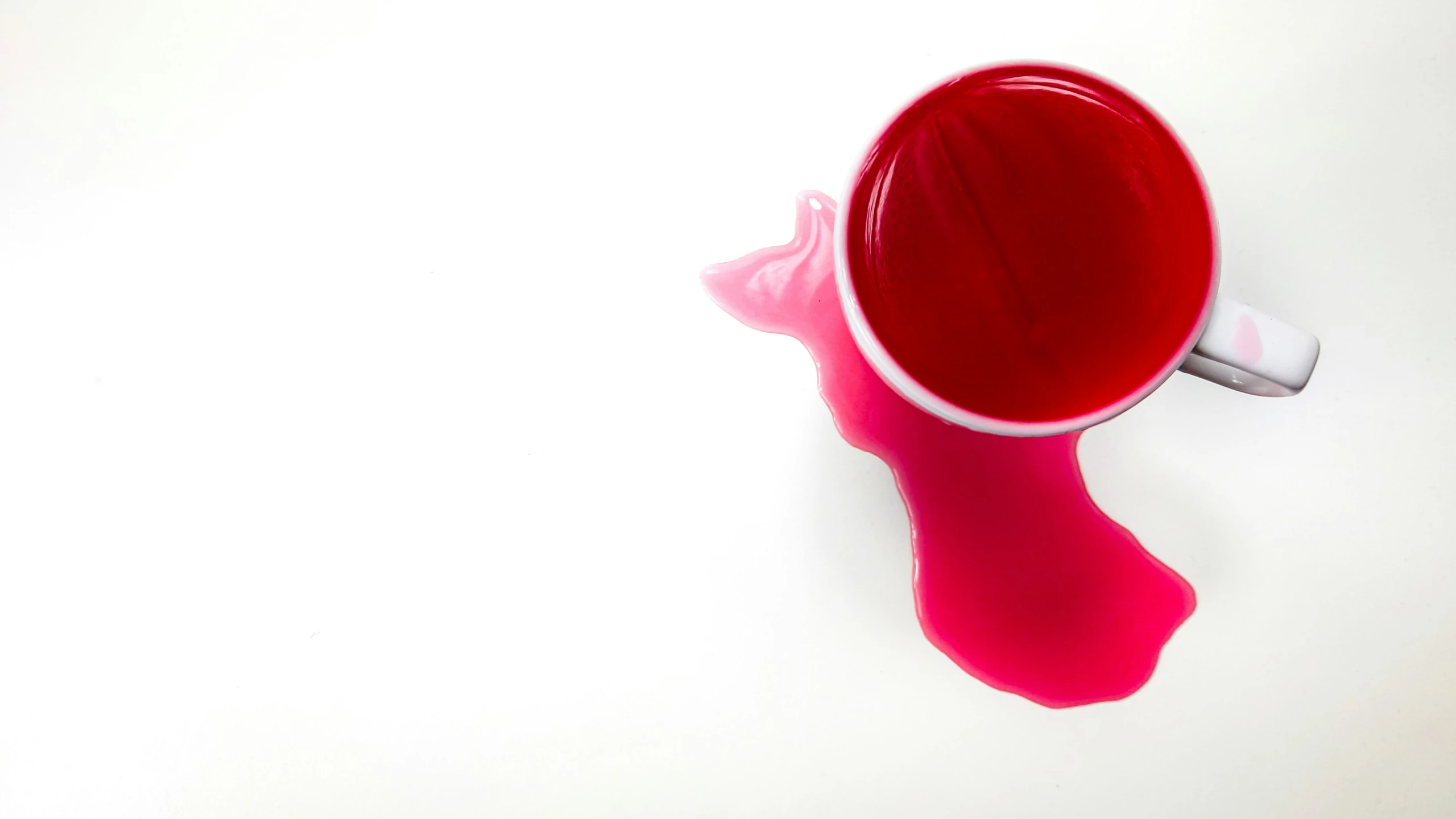 a cup with pink liquid is on top of the white surface