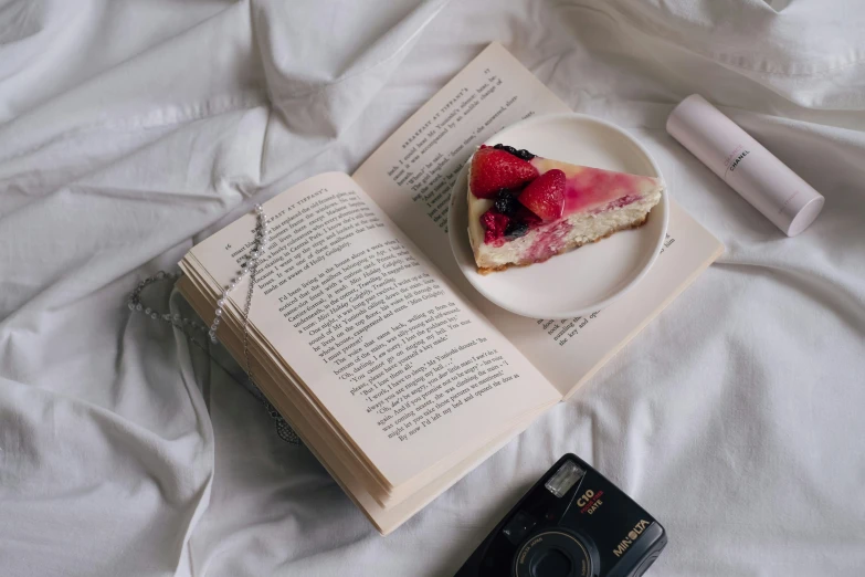 a heart shaped cheesecake with raspberries on a plate next to an open book