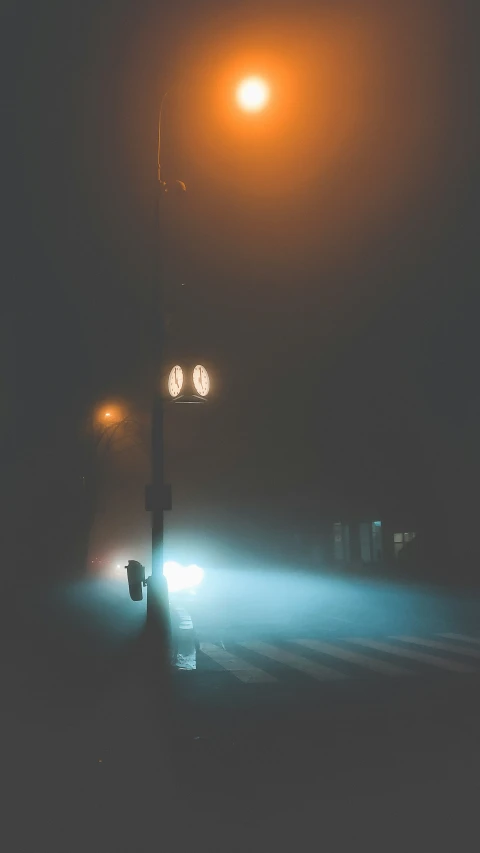 fog on a street light at night with one way traffic lights shining on the ground