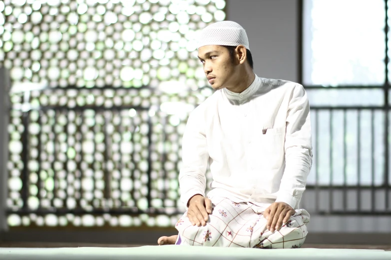a man is sitting on the ground wearing a white outfit