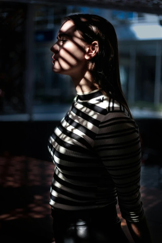 a woman in striped shirt standing next to a building