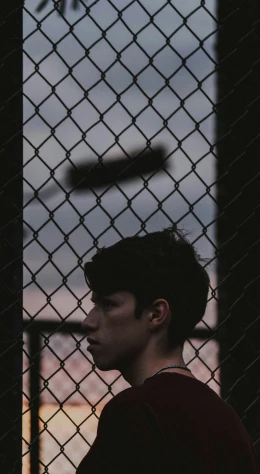 a young man standing in front of a fence