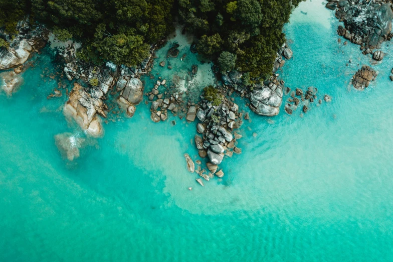 a blue ocean with rocks in the middle and some trees in the middle