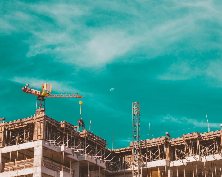 a po of an unfinished building with a crane and blue sky in the background