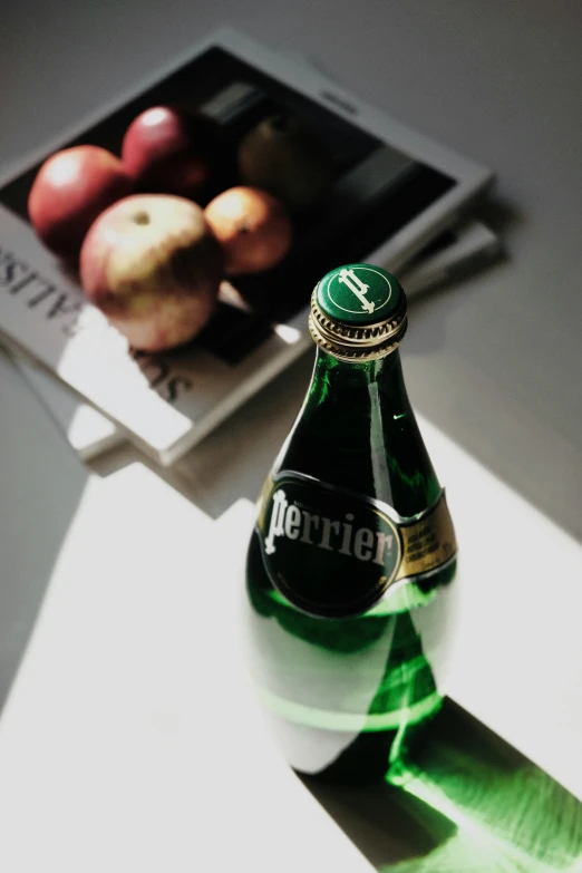 a bottle sitting on top of a table with a bunch of fruit behind it