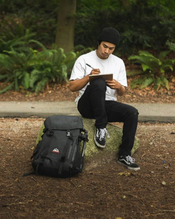 a man is sitting in the forest reading a book and writing