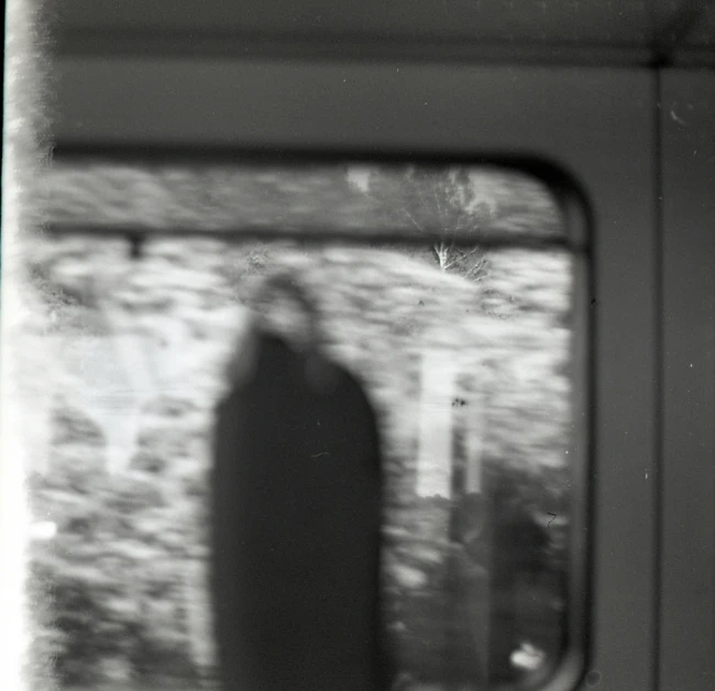 a person sitting inside a train, casting a shadow