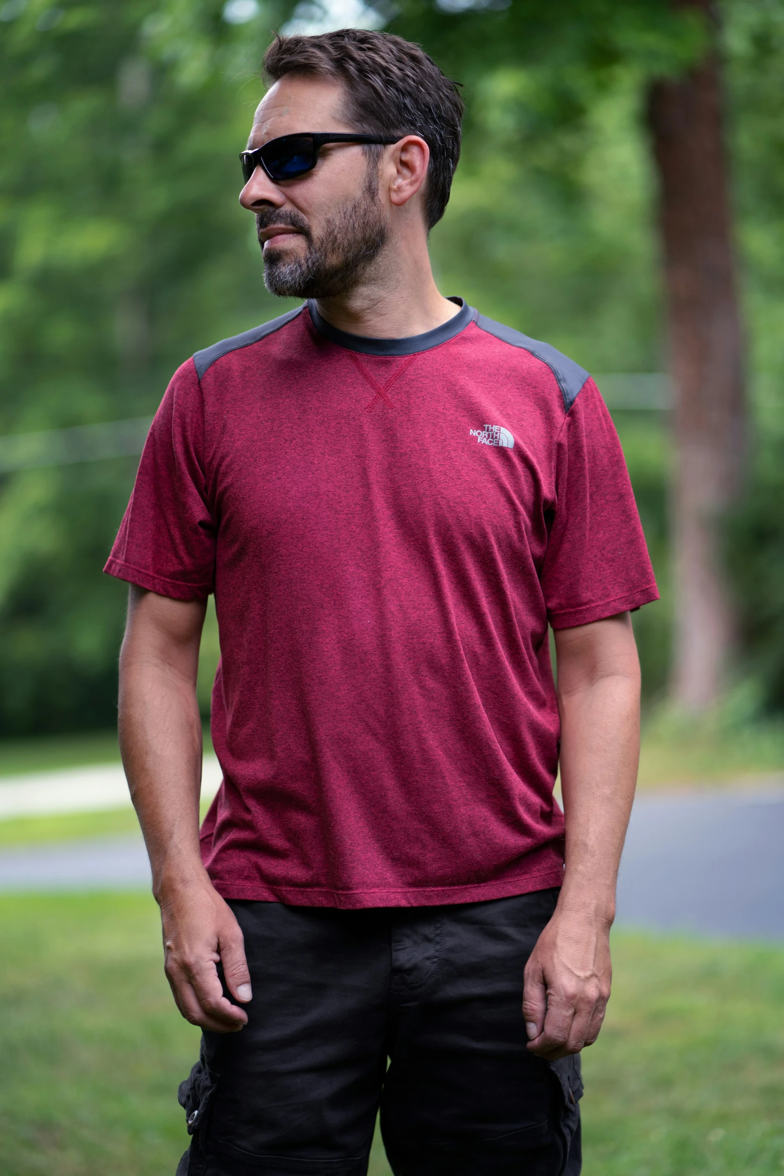 man wearing sunglasses standing on grass near park