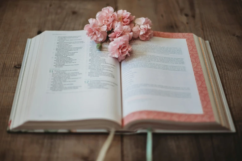 open book with floral arrangement on wooden table