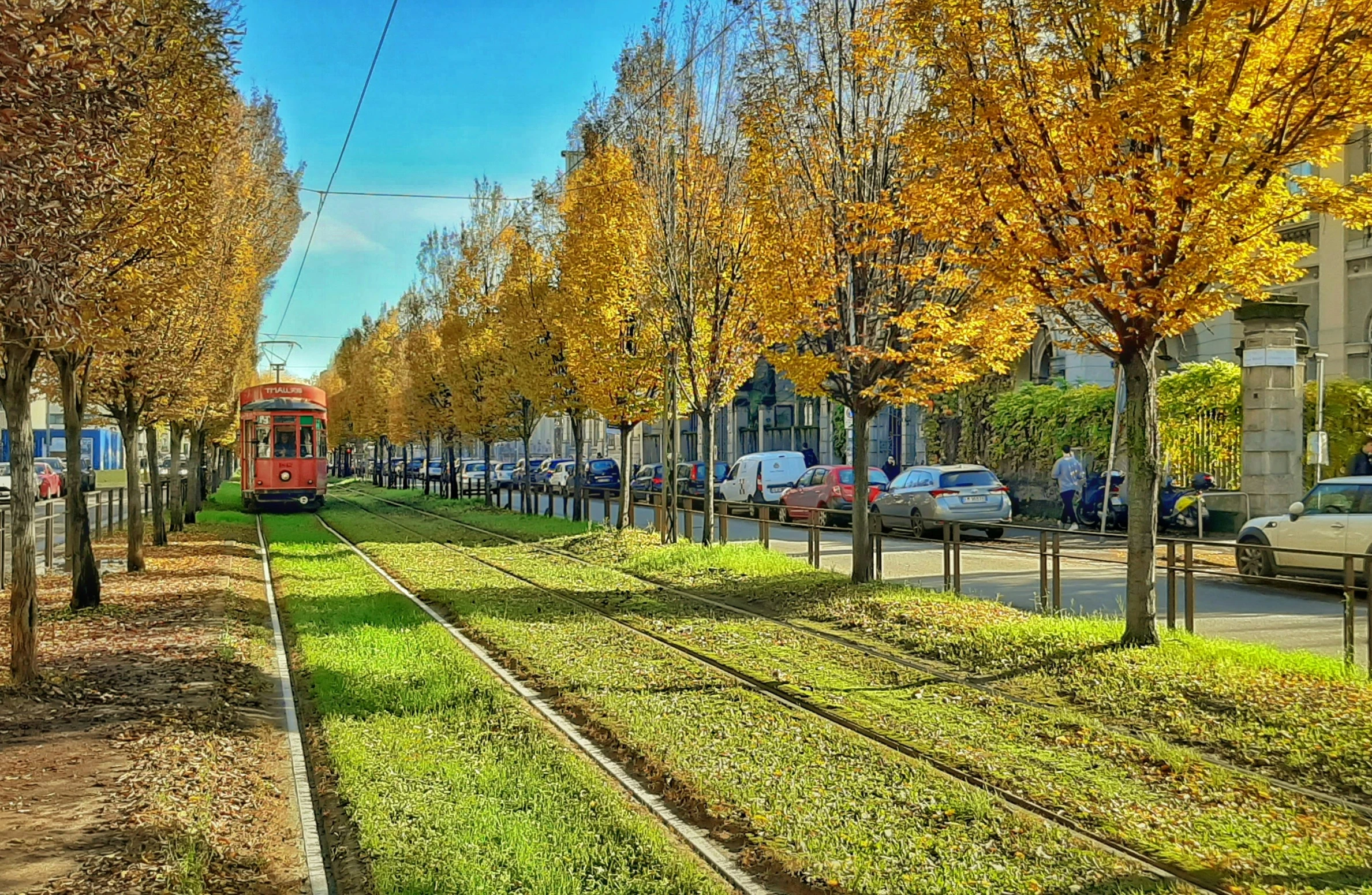 a red train traveling down tracks next to a street