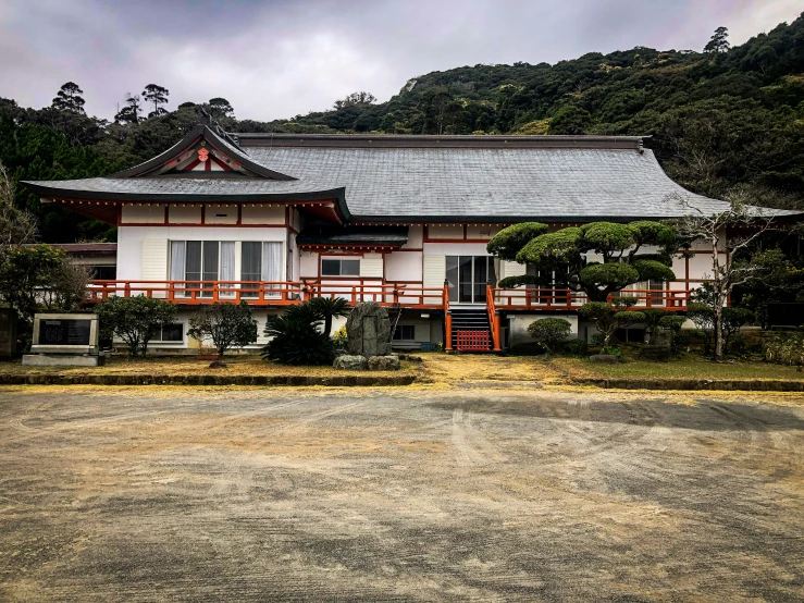 a picture of a white and red building in front of a forest