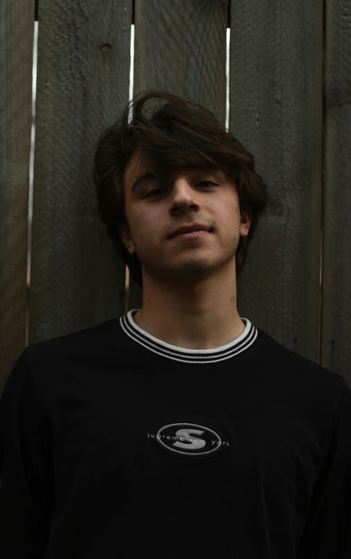 a man looking at the camera and standing near a fence