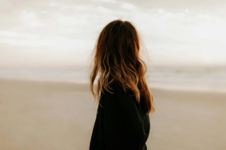 a long haired woman looking out at the ocean