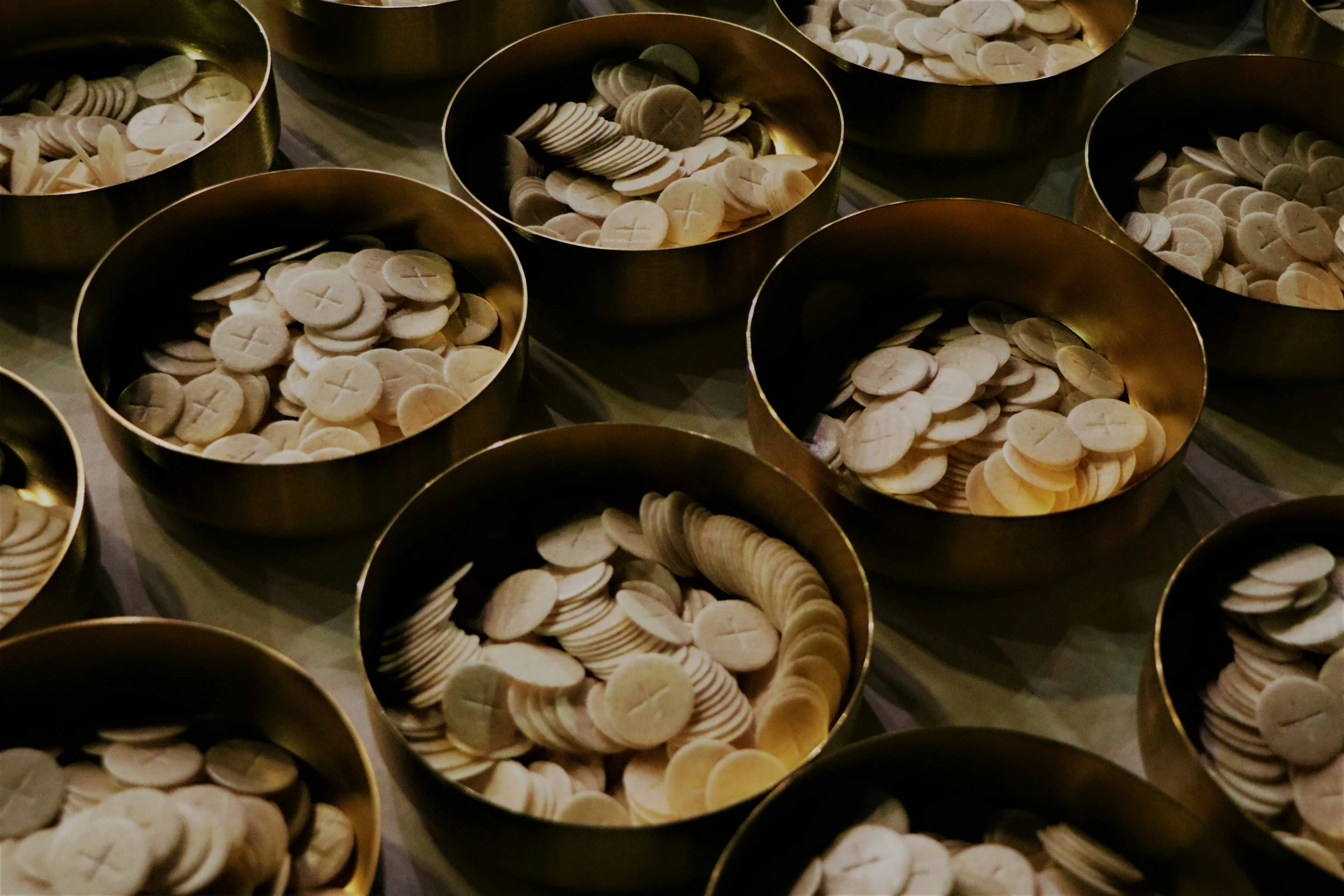 several gold dishes full of silver objects in them