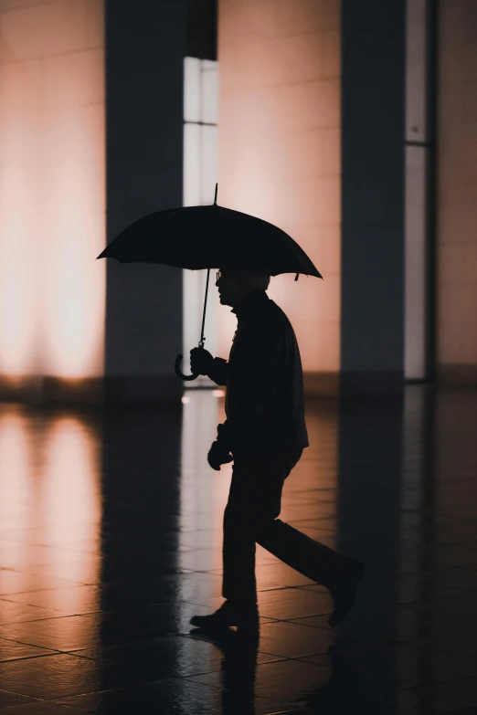 a man walking down a hall holding an umbrella