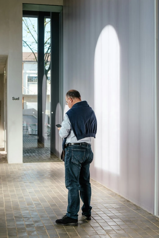 the back of a man standing and looking at his cell phone